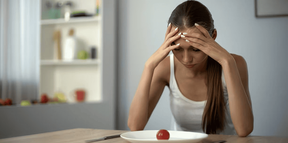 Exhausted woman with head resting on hand at dining table, eyes closed